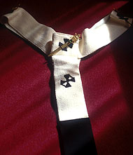 Pallium na may disenyo ng limang krus at tatlong pins. Sinusuot ng mga arsobispo, mga kardinal at santo papa.