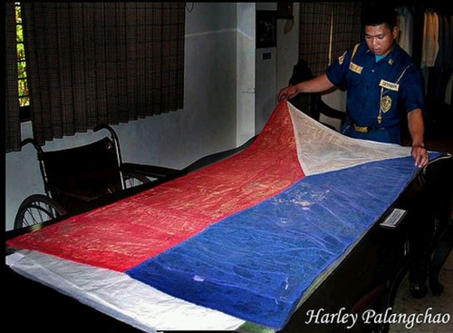 Kuya guard, hinahawakan ang bandilang nagmula pa sa panahon ng himagsikan.  Mula kay Harley Palangchao