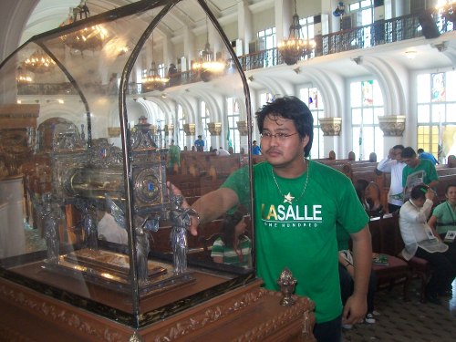 Si Xiao Chua habang nagbibigay ng respeto sa relic o isang piraso ng buto ni San Juan Bautista de La Salle noong Sentenaryo ng La Salle sa Pilipinas, June 16, 2011. Hindi man Katoliko, nakikibahagi ako sa hiraya ng La Salle: Religio, Mores, Cultura. Mula sa Sinupan ng Aklatang Xiao Chua.